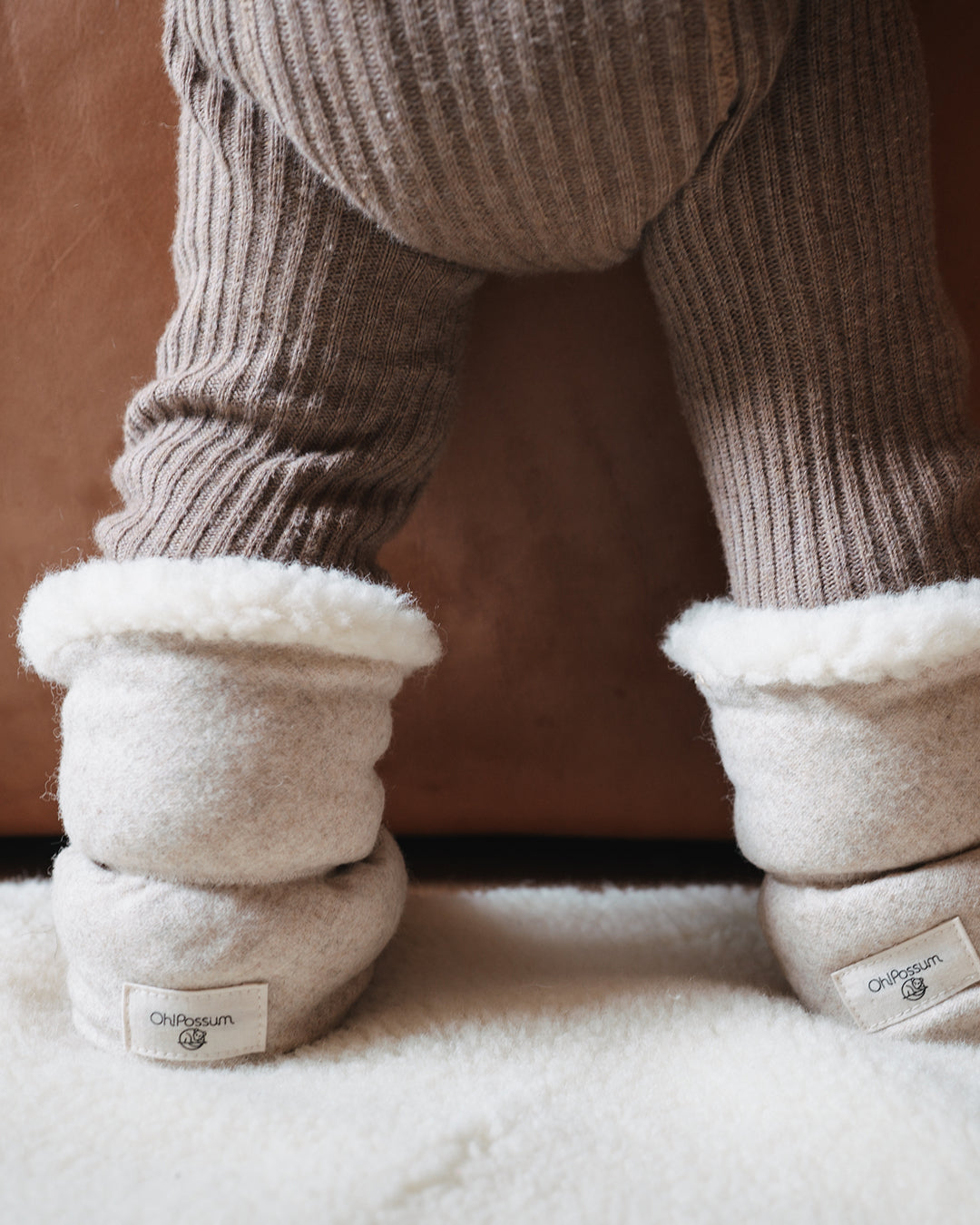 Babyfüße eingekuschelt in handgemachte Booties aus Merinowolle