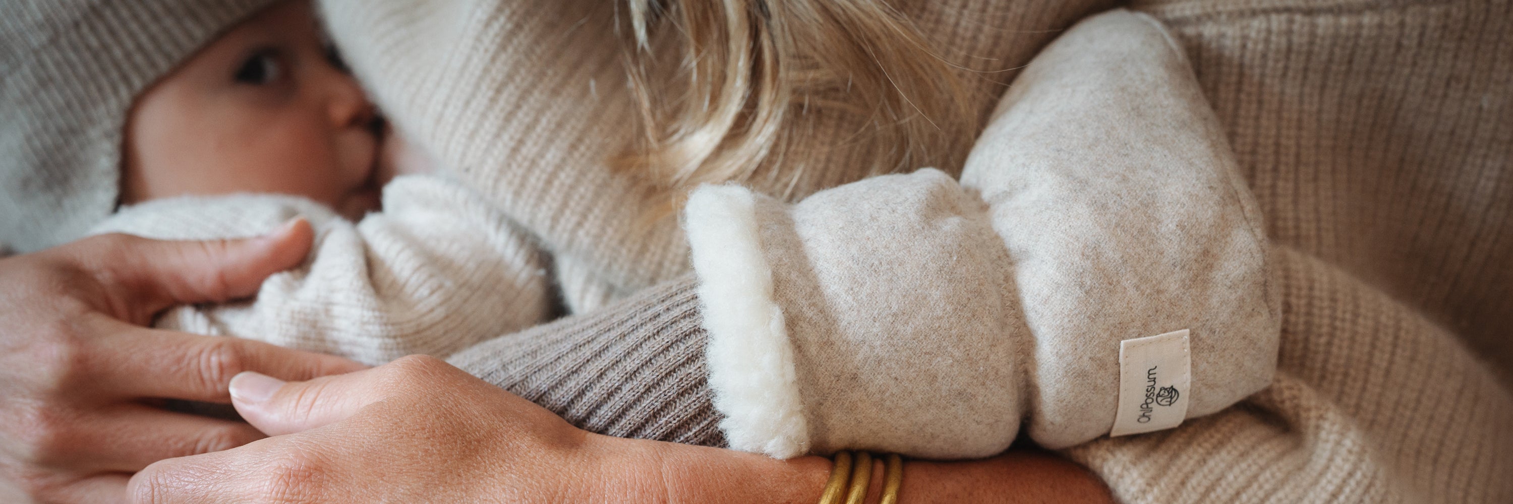 Baby im Arm der Mutter mit Baby Booties in Farbe Cashmere